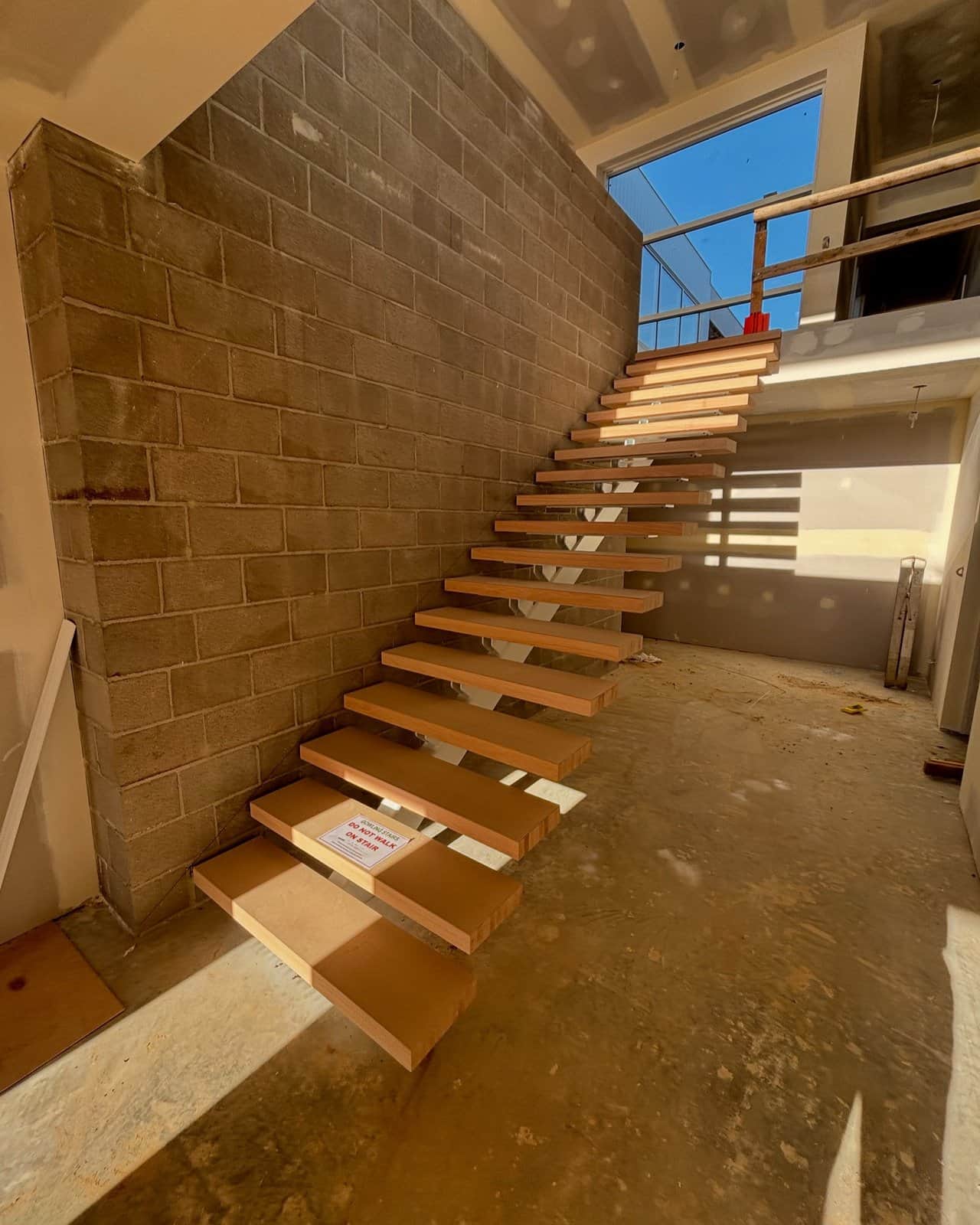 Floating timber staircase against a rammed-earth wall in Toorak